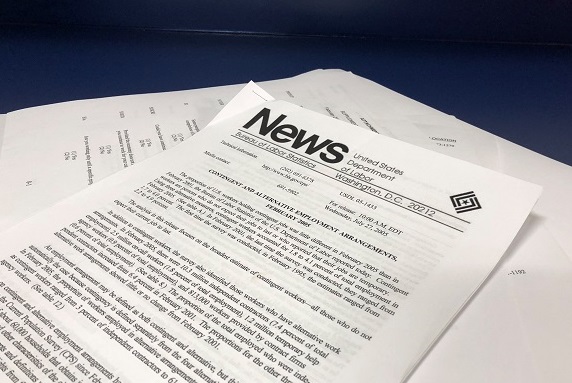A news article printed and laying on top of other documents
