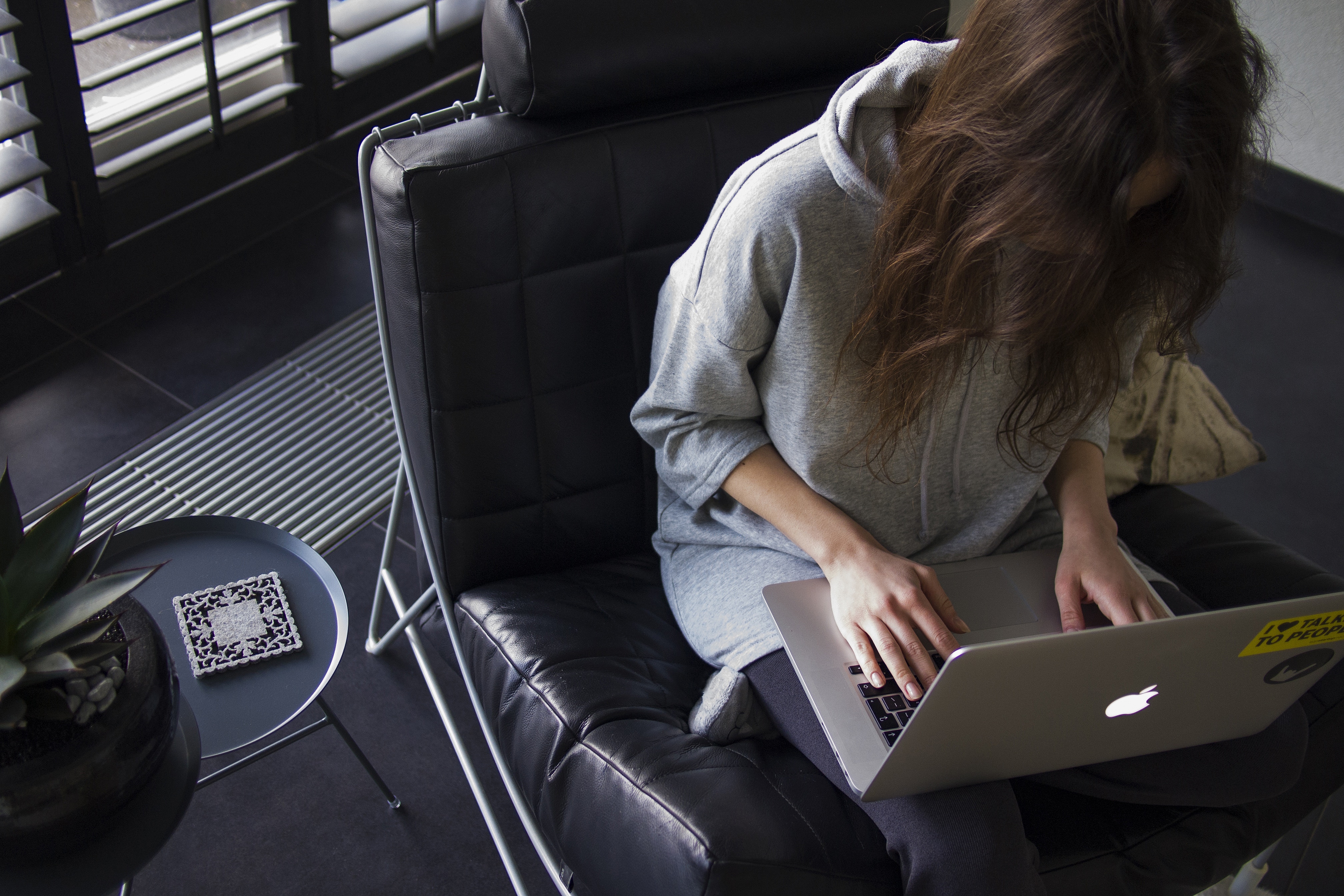 a woman sits in a comfortable black chair and works on a computer